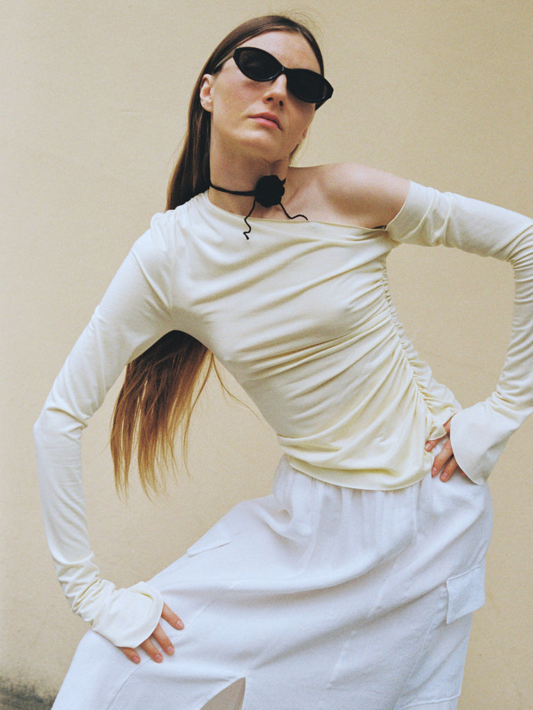 SS25 Atelier Magata Butter Yellow Top Asymmetric Shoulder Long Sleeves black rosette black sunglasses white skirt