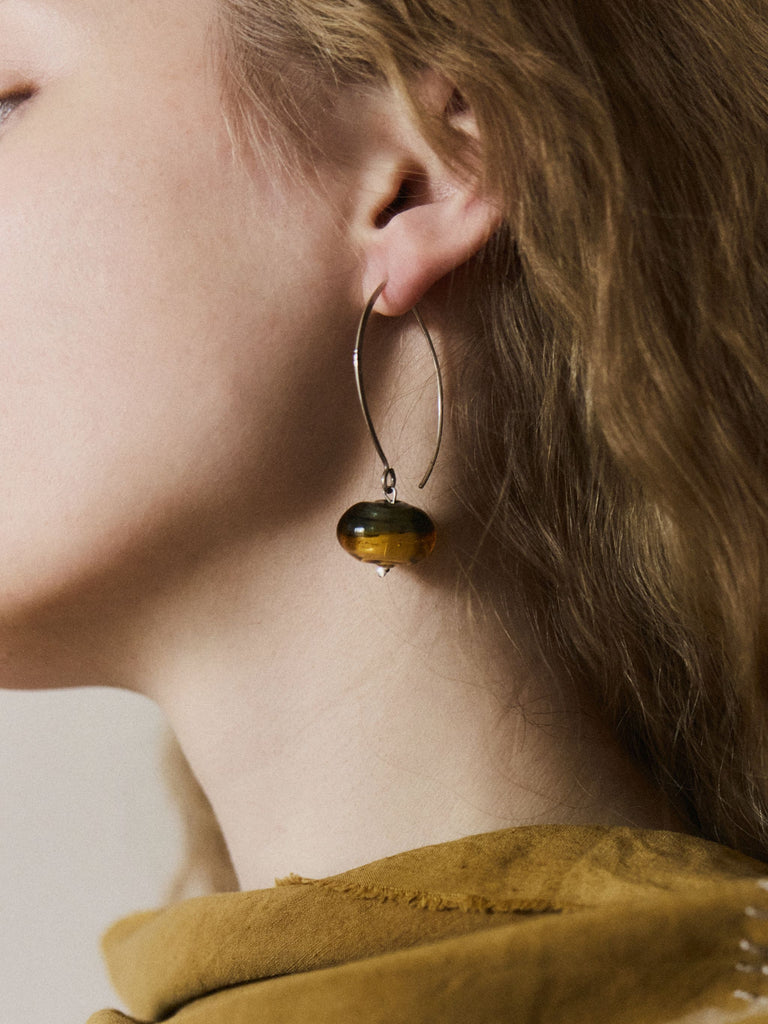 Murano glass and silver hoop earrings worn by a woman with blond long hair