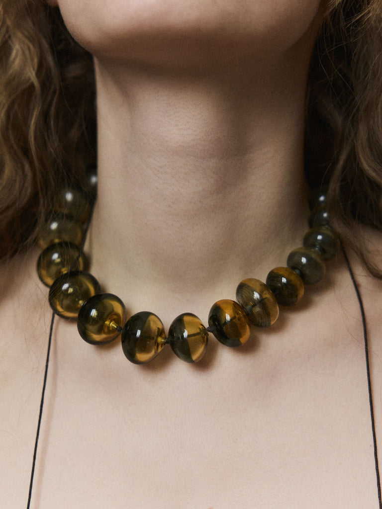 Close-up of a person wearing a yellow green Murano glass beaded necklace