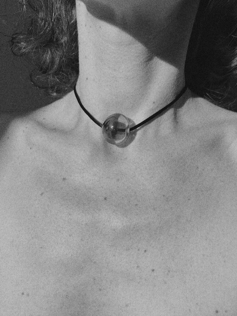 Necklace with a clear Murano glass bead worn by a person