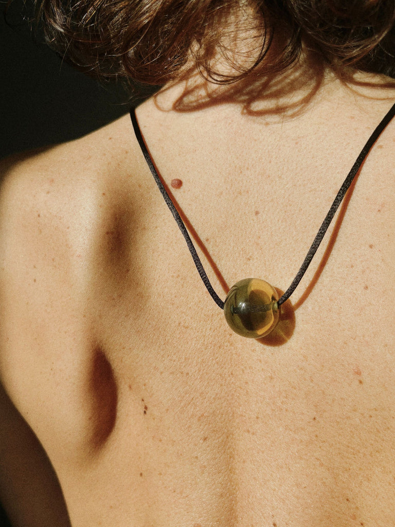 Pendant necklace with a large yellow green Murano glass bead on a person's neck