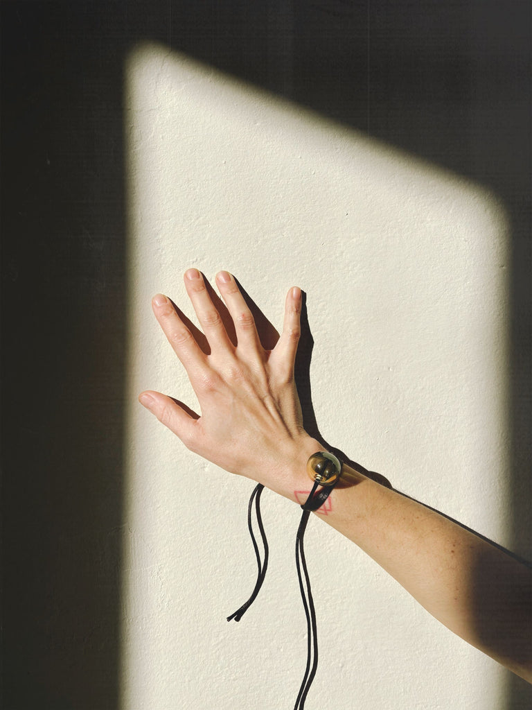 Hand with a Murano glass bead bracelet reaching out against a light and dark background