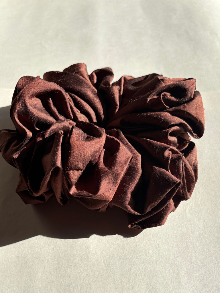 Brown silk scrunchie on a light beige background