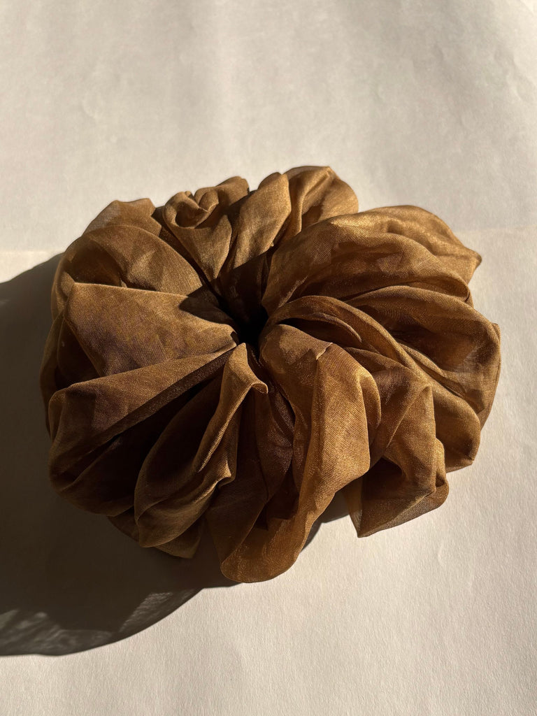 Brown amber silk scrunchie on a beige background