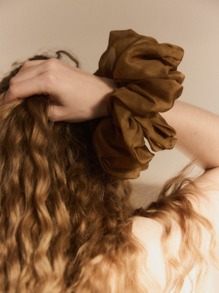 Worn view of the amber Fiorenza cuff by Magata on the wrist, styled in hair, showing the sculptural ruffled volume in natural light.