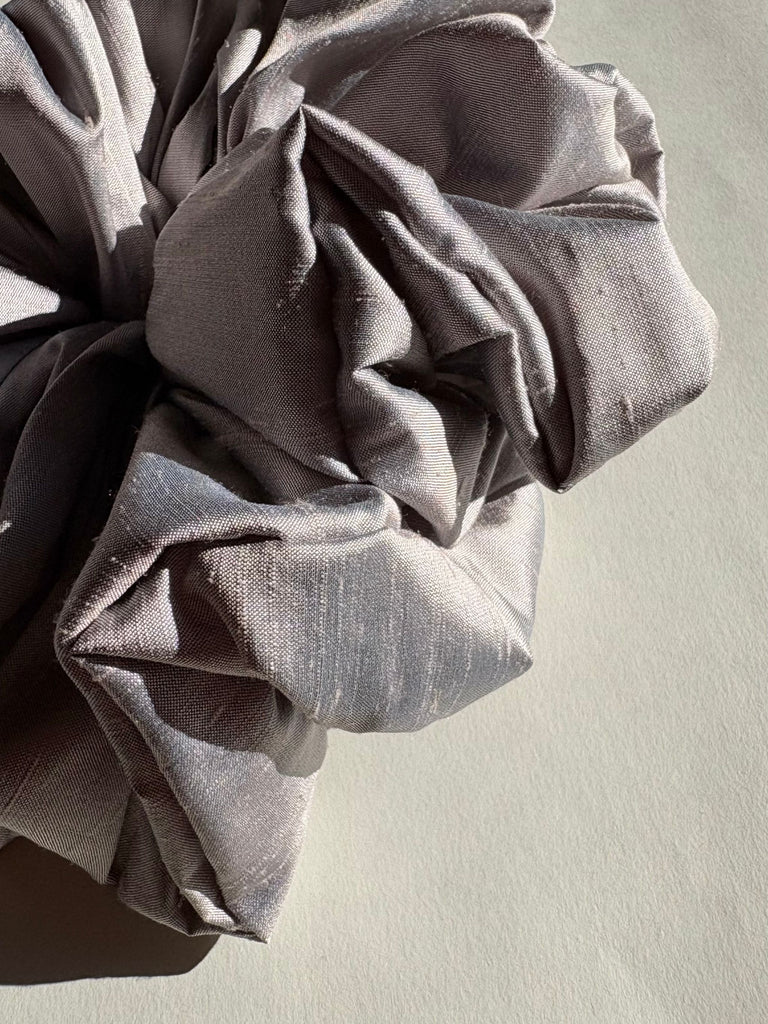 Close-up of a textured silver lilac fabric with folds on a light beige background