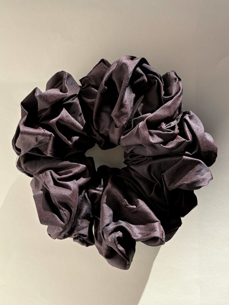 dark purple silk scrunchie on beige background