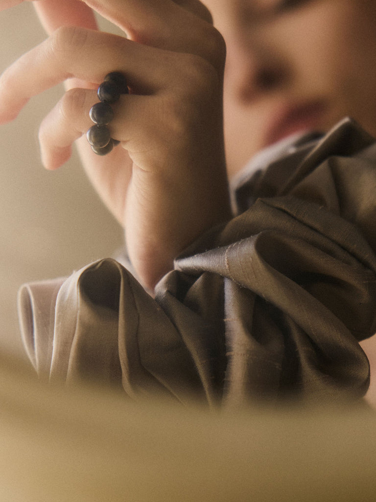 Close-up of a person wearing a blue Sodalite beaded ring with a blurred background